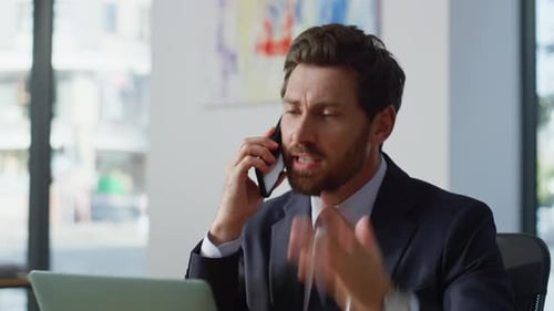 Businessman Talking on Cell Phone at Office Desk