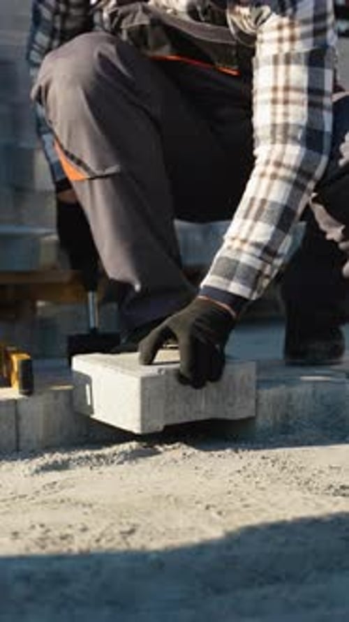 Paver Installer Working Near a Cottage Construction Site