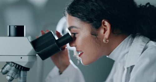 Young Adult Using Microscope in Bright Laboratory