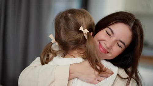 Schöne Mutter umarmt kleine Tochter Entzückende kleine Kind-Tochter umarmt Mama