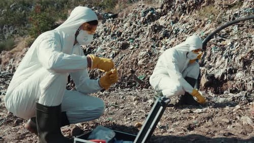 Scientists Examining Waste in Landfill with Protective Gear