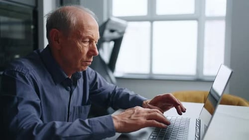 Senior Man Using Laptop Computer in Modern Home
