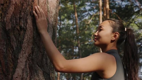 Young Asian Woman Meditating Near a Tree in the Forest