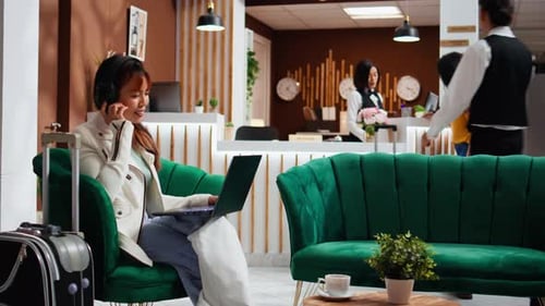 Asian Woman Enjoying Movie on Laptop in Hotel Lounge Area