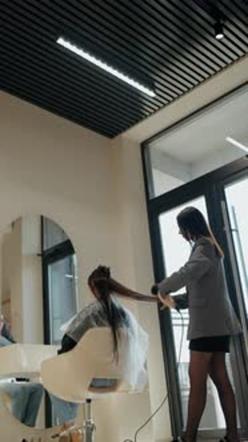 Hair Stylist Uses Blow Dryer in Salon