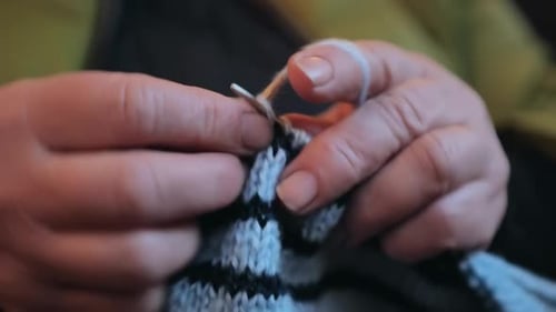 Hands Knitting Blue and Black Woolen Fabric