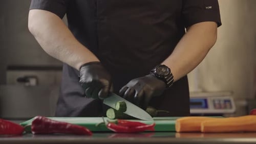 Chef slices cucumber on cutting board