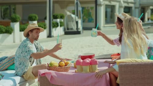 Friends Toasting at Beachside Table with Fruit
