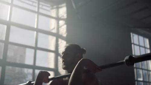 Shirtless sportsman doing front squats with heavy barbell during gym training session
