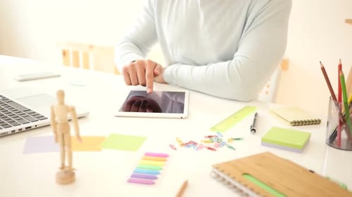 Man Using Tablet at Desk with Laptop