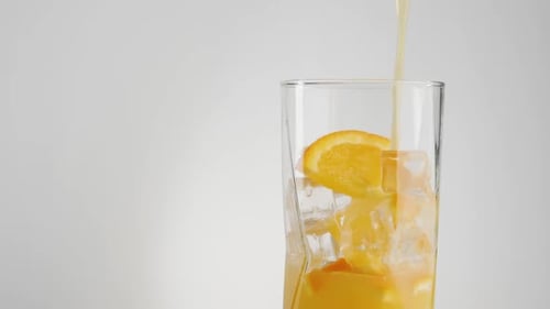 Pouring Refreshing Orange Juice into Glass with Ice