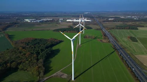 Wind farm Windmill turbines near highway clean energy. Dramatic aerial view flight drone