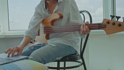 Musician Plays Bass Guitar Indoors During the Day