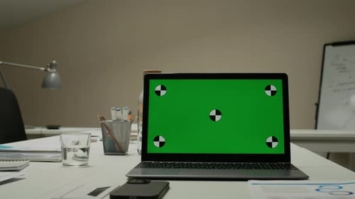 Laptop on Desk in Boardroom Displaying Green Mockup Screen at Office