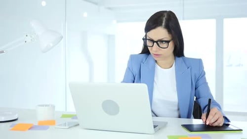 Woman Working at Desk on Laptop and Graphic Tablet