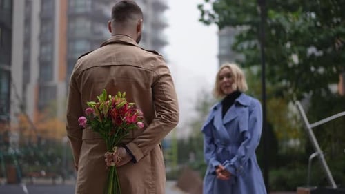Man Surprises Woman with Flowers in Urban Setting