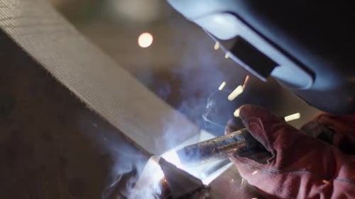 A Skilled Welder is in Action Creating with Beautiful Sparks and Smoke Effects During the Job Stock