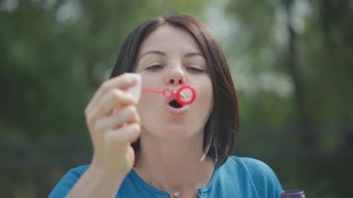 Woman Blowing Bubbles Outside on Sunny Day