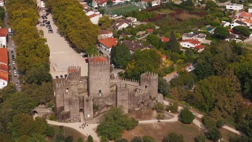 aerial view of guimarães castle surrounded by trees and historic cityscape