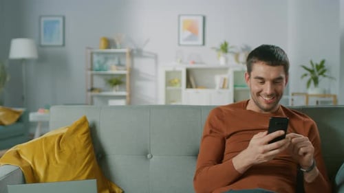 Man Relaxing on Sofa Using a Mobile Phone