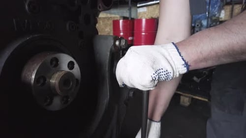 Mechanic Adjusting Large Engine in Workshop