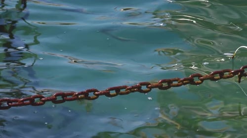 Rusty Chain Links On Turquoise Sea Water