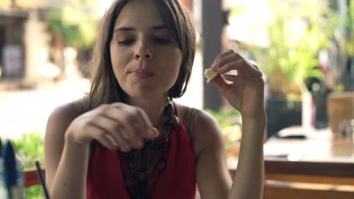 Young Woman Eating Snack and Drinking Cocktail in Cafe in City 30s
