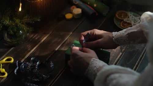 Hands Tying Ribbon on Green Christmas Gift