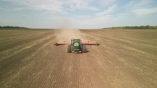 Green tractor seeding wheat on the field