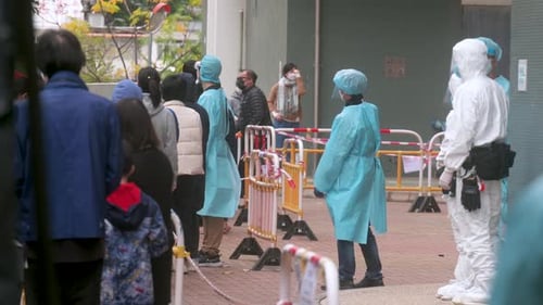 People Queueing in Line Wearing Protective Suits