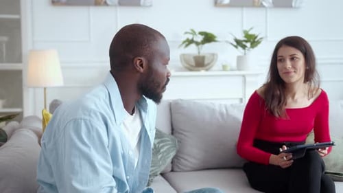 Un homme et une femme sur un canapé partagent une conversation familière animée