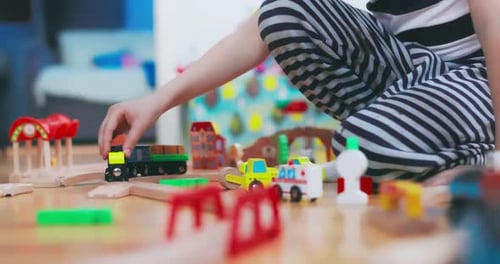 Child is Playing with Toy Railway Road at Home or in Kindergarten on Floor