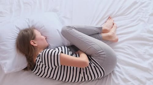 Douleur à l'estomac chez une femme couchée dans son lit, elle est déprimée