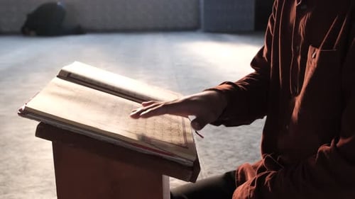 Seitenansicht eines Mannes, der das islamische Religionsbuch Koran mit seinem Finger liest, religiöses Buch mit Ara