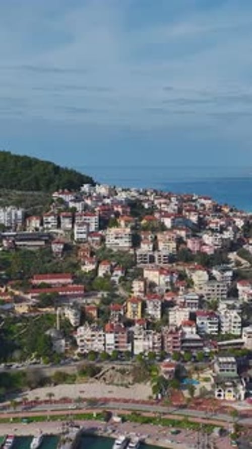 Vertical Video of a Small Coastal Cityscape Captured From Above With a Harbor Boats and a Beachfront