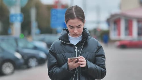 A Girl Walks Through Town and Looks Through Her Phone