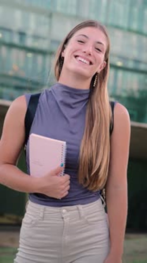 Retrato vertical de una mujer rubia adolescente alegre y adorable posando para un ascenso universitario