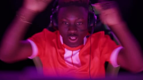 Young Adult Gamer Celebrating Win in Purple Light