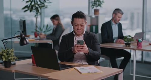 Man at Desk Using Phone in Modern Office
