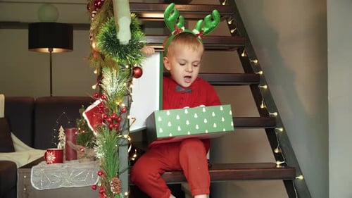 Upset and angry toddler boy opens his Christmas gift and gets disappointed throwing down the present