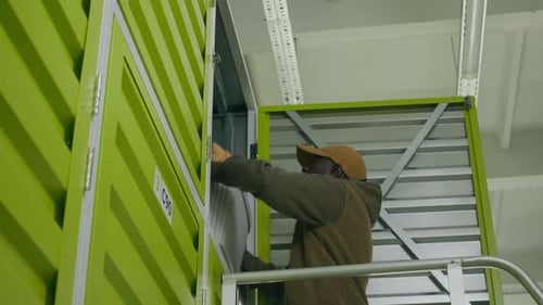Un homme noir sort une boîte de l'unité de stockage en libre-service