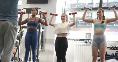 Multiethnic Gym Class Exercising with Dumbbells Indoors