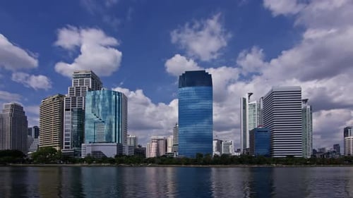 Bangkok Scenic cityscape with skyscrapers by the water under a cloudy blue sky. Timelapse