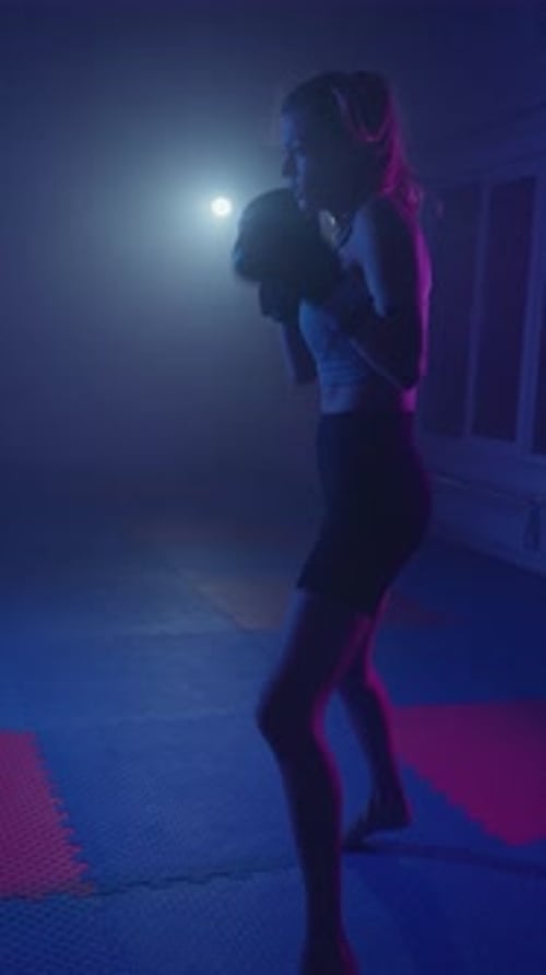 Intense Boxing Training Session at a Neonlit Gym with a Dedicated Female Athlete and Her Coach