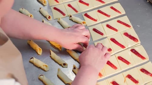 Gros plan de bagels tordus à la main pour femmes fourrés à la framboise dans la pâte Women's Hands Twist