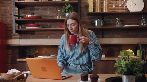 Woman Using Laptop with Man in Cozy Kitchen