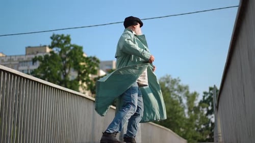 Bottom Angle View of Cheerful Senior Man Spinning Having Fun on Pedestrian Bridge in Town