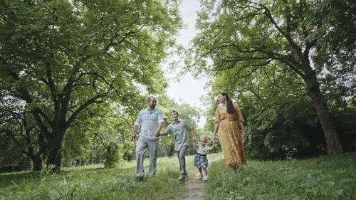 Family Strolling Near Trees in Countryside Ground Level Zoom Out View of Happy Parents and Kids