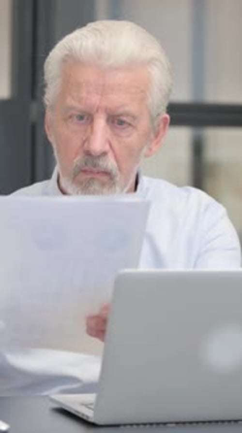 Senior Man Working with Laptop and Documents Indoors