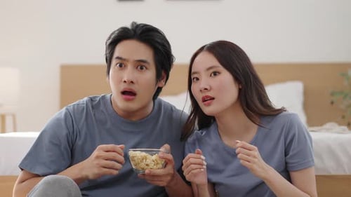 Couple Watches with Popcorn in Bright Bedroom